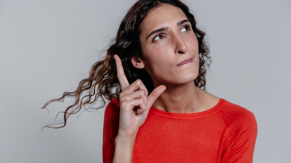 Contemplative woman pointing upwards, thinking deeply in a casual setting.